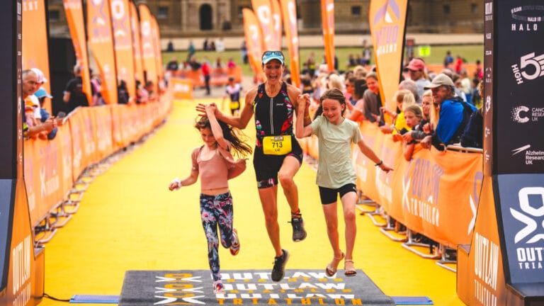 Competitor crosses the finish line with her kids at Outlaw Half Holkham