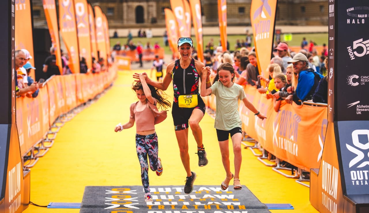 Competitor crosses the finish line with her kids at Outlaw Half Holkham